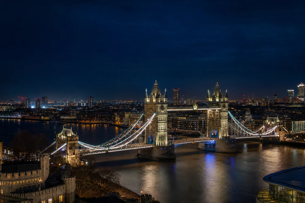 Blue-hour elevated view of London's Tower Bridge, the River Thames, and the United Kingdom capital at night.